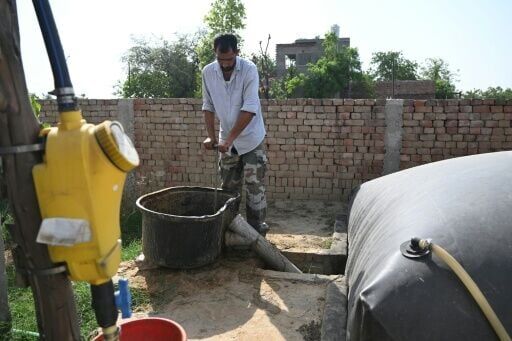 A resident pouring cow dung into his biogas plant at a village in Uttar Pradesh