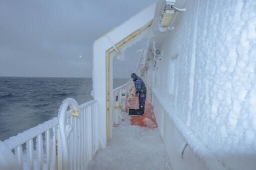 Voyage to the north: a crew member clears ice from the deck of Greenland's Sarfaq Ittuk ferry