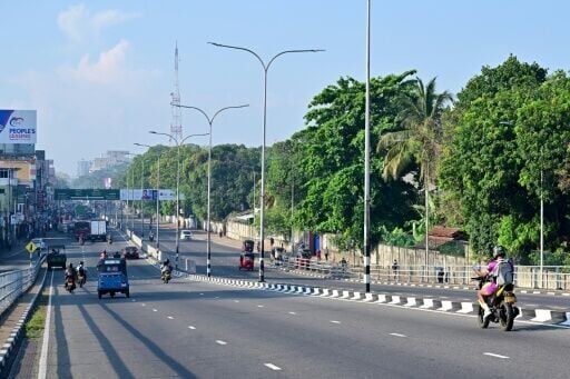 Commuters ride along a deserted street in Colombo on March 25, 2026. Sri Lanka has ordered street lights, neon signs and billboard lighting to be switched off as part of measures to cut energy consumption by 25 percent.