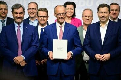 German Chancellor Friedrich Merz (C) poses with his cabinet after signing a coalition deal to form the country's new government in May 2025