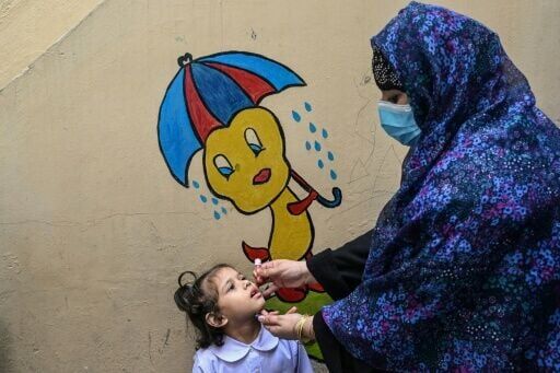 A healthcare worker administers polio drops during a door-to-door poliovirus eradication campaign in Lahore