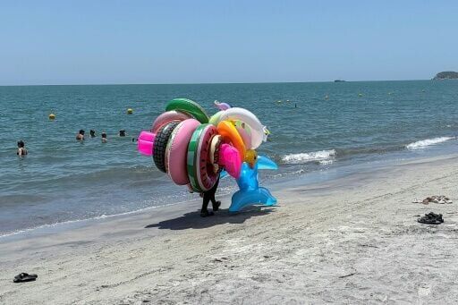A seller of inflatable floats walks along the beach in Santa Marta, a major Colombian tourist destination, where violence lurks beneath the surface