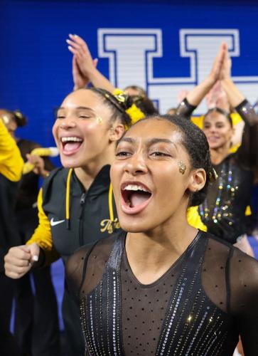 Railey Jackson, front, and Makayla Green cheer with the team as Olivia Kelly concludes her beam routine at the NCAA Lexington Regional