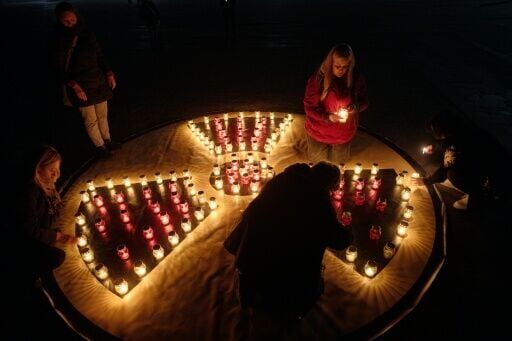 People light candles set in shape of a radiation sign in front of a memorial for Chernobyl victims in the town of Slavutych
