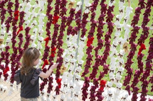A child stands near a display of 20,000 stuffed teddy bears that activists say represents a Ukrainian child abducted by Russia since the start of the war