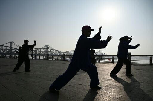 People perform tai chi on the waterfront of the Yalu river