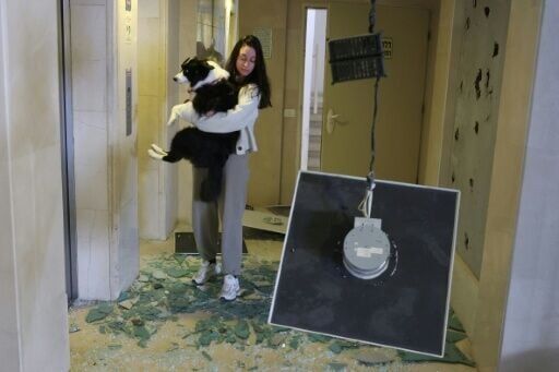 A woman carries her dog in a building damaged in an Iranian missile strike in Tel Aviv