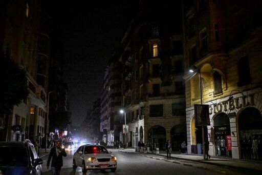 People walk past shops closed early in Cairo under a government-ordered curfew