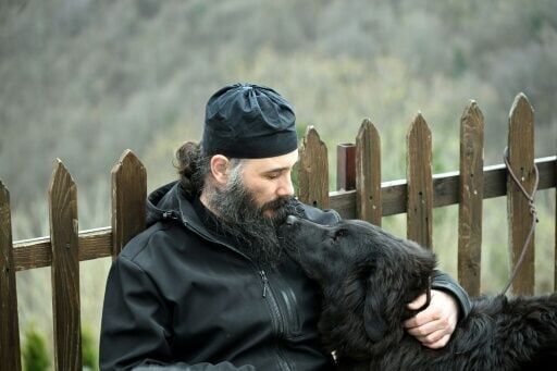 Orthodox priest Father Porfirij plays with a Karaman sheepdog