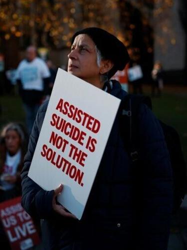 A campaigner against the assisted suicide bill holds a placard at a demonstration in November 2024