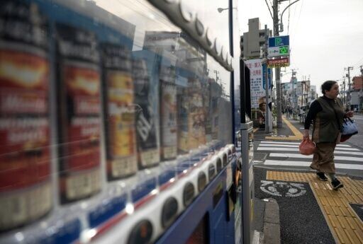 A woman walks past a vending machine setup next to a major road in Tokyo's Bunkyo district on April 14, 2026