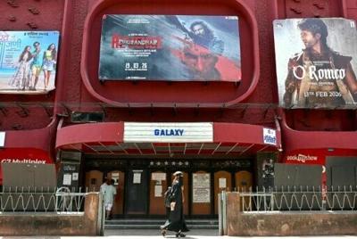 A woman walks past a poster of Indian Hindi-language spy action thriller film Dhurandhar: The Revenge