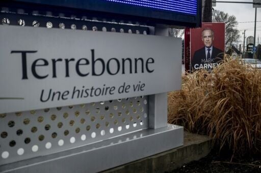An election campaign sign showing Prime Minister Mark Carney is displayed along a street in Terrebonne, Canada