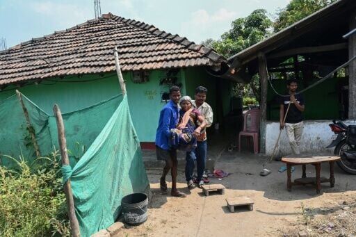 Tama Jogi, who lost her legs in a landmine explosion, being helped by family members in Awapalli village