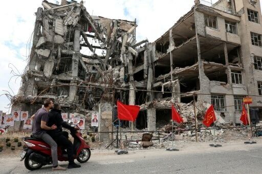 Iranians stop to look at portraits of victims reportedly killed in a US-Israeli airstrike on a residential building in Tehran