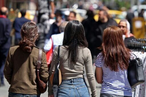 Iranian women walk along a busy street in Tehran