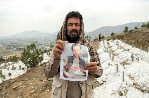Homayoun Anwari holding a portrait of his late brother Hamid Anwari, who was killed by Pakistani airstrikes on a drug rehabilitation centre