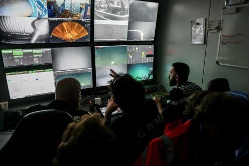 Experts monitor the underwater robot's slow descent on screens