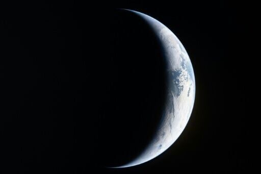 This handout picture by an Artemis II crew member provided by NASA shows a sliver of Earth illuminated against the blackness of space through the window of the Orion spacecraft on April 4