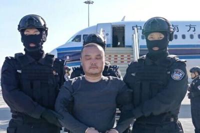 This frame grab from a handout video released by the Chinese Ministry of Public Security shows China-born accused scam boss Li Xiong arriving at an airport in handcuffs