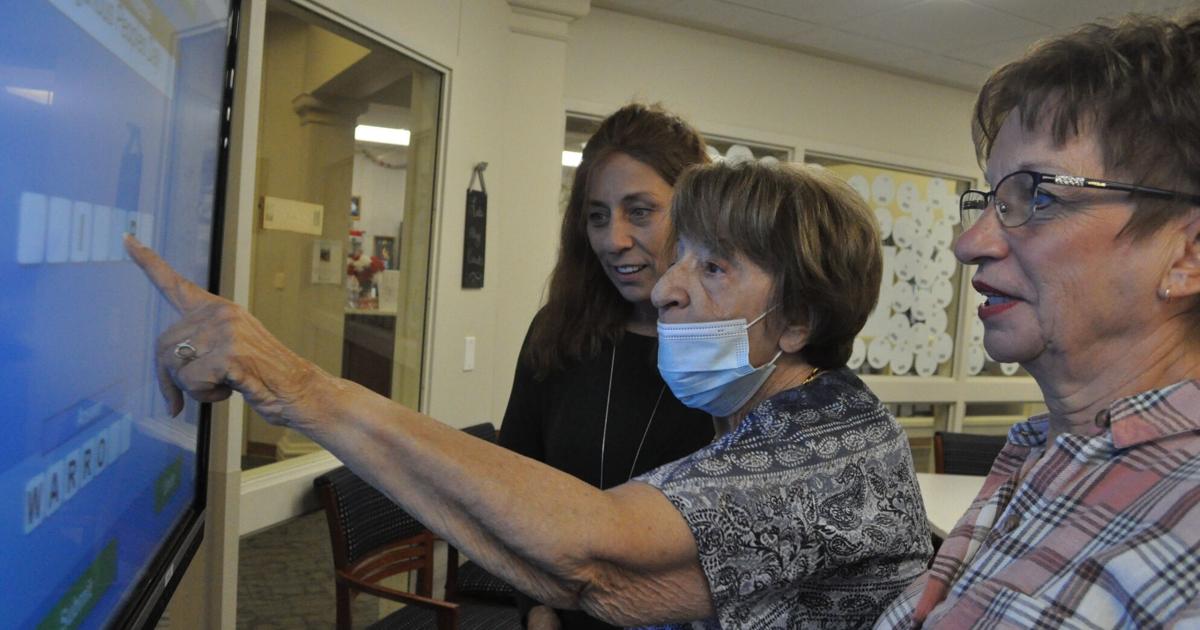 Beth Alberts and Kathy Nannen assist resident Judy Paolini
