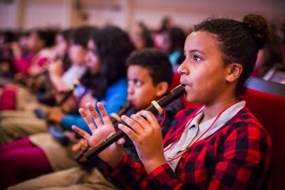Students playing recorders from their seats