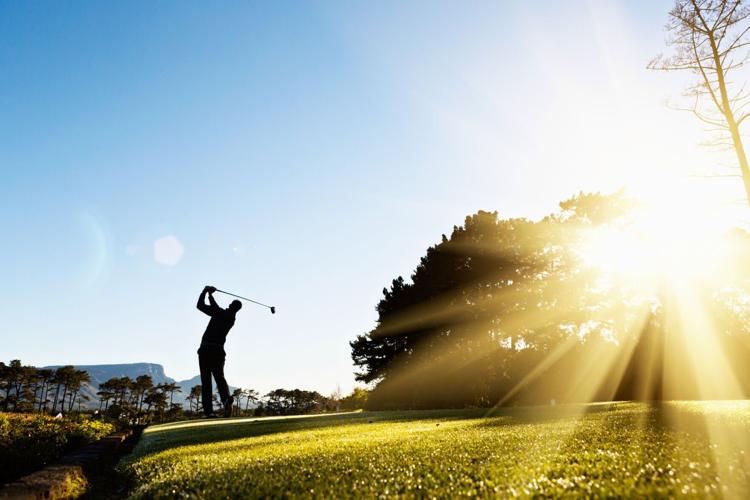 Silhouette as young golfer swings on beautiful, sunlit course