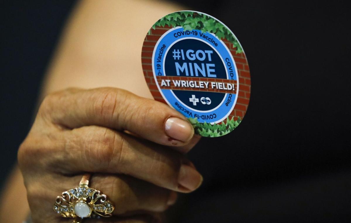 Eustorgia Alcarav, 72, holds a sticker after she received the first dose of the Pfizer COVID-19 vaccine at the American Airlines Conference at Wrigley Field on Monday, April 5, 2021.