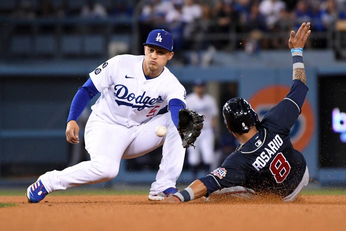 Los Angeles Dodgers shortstop Corey Seager, left, prepares to catch a ball while Atlanta Braves' Eddie Rosario attempts to steal second during the third inning in Game 5 of the 2021 National League Championship Series at Dodger Stadium on Thursday, Oct....