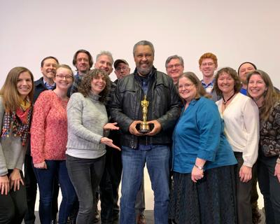 A group of faculty members stand by Kevin Willmott, who holds his Academy Award in the center