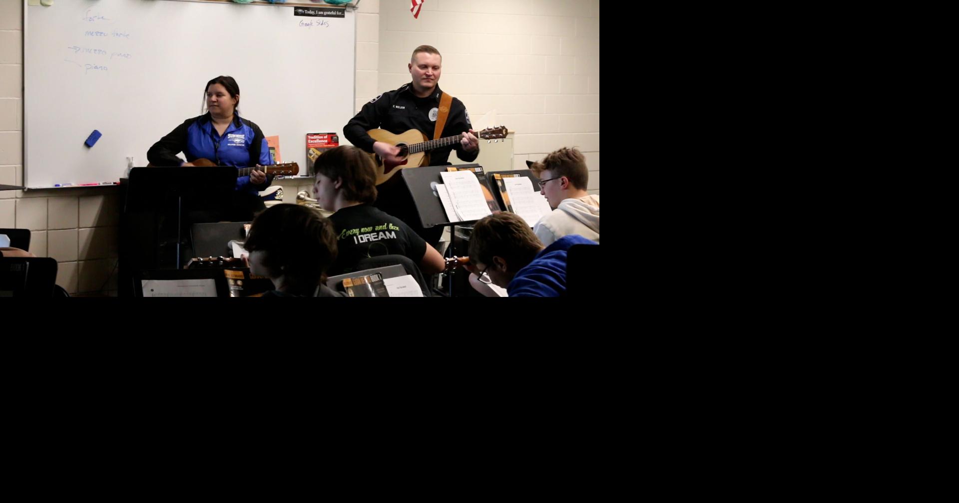 Officer Cody Weldon helping Sunrise Middle School students learn guitar