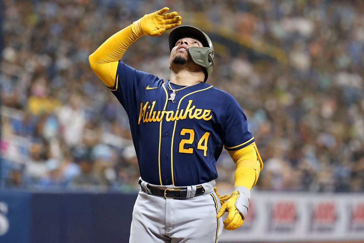 Milwaukee Brewers' Willy Adames, left, places a cheesehead on