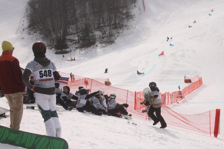 Snowboarder walks past group of competitors