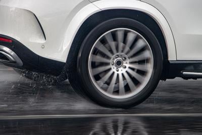 Close up rear wheel of a car driving in rain/on wet road (stock)