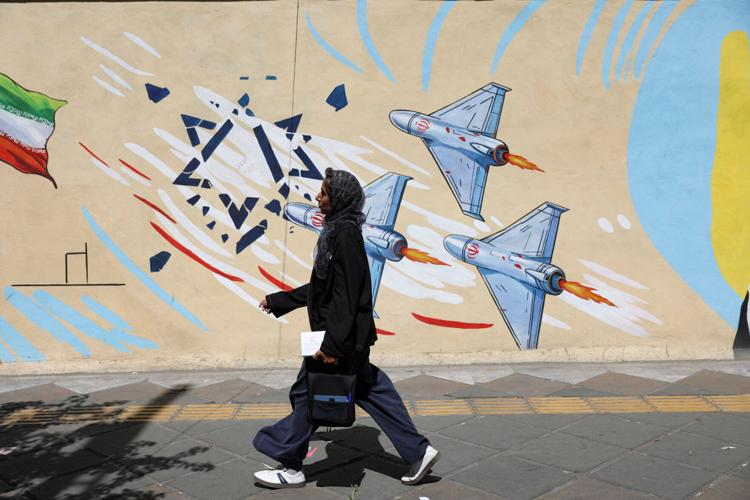 An Iranian woman walks past an anti-Israeli mural, in Tehran