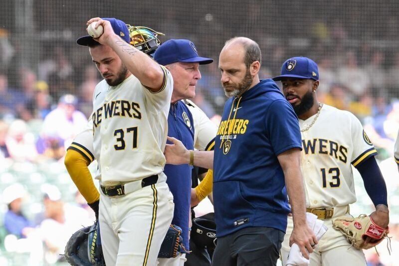 Brewers reliever DL Hall (37) leaves the game with an injury as he is escorted off the mound against the Giants by athletic trainer Brad Epstein in the fifth inning on Thursday, June 4 at American Family Field.