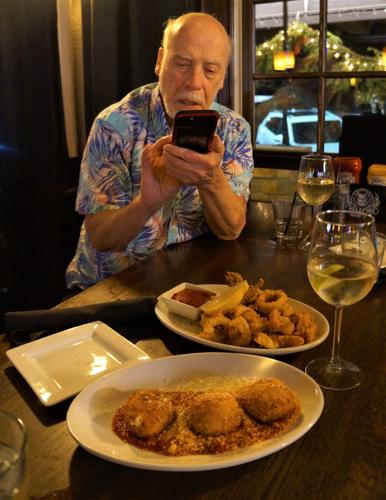 Pete Oehmen takes a photo of Tuscan Tavern & Grill appetizers for posting to the "Aloha Boys" Facebook page