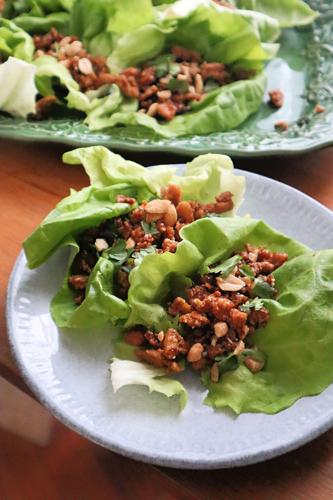 Fried tofu is topped with chopped peanuts and cilantro inside a lettuce leaf wrap.