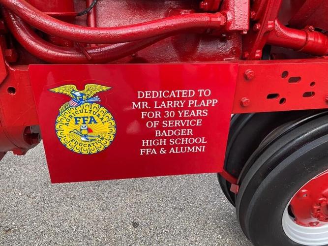 A sign has been posted on a restored tractor indicating that the tractor is in honor of Larry Plapp