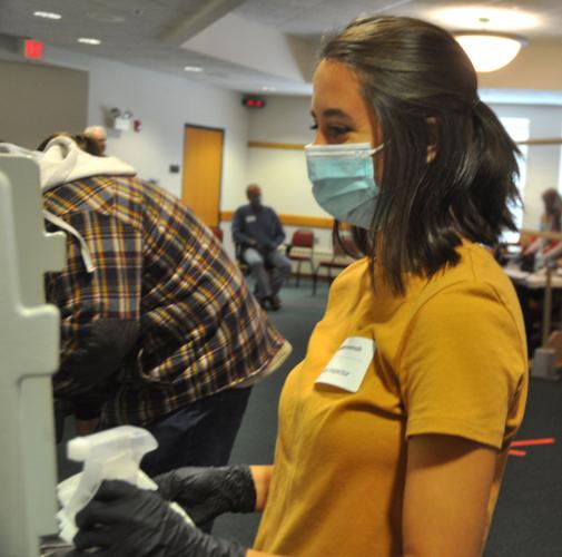 Election inspector Cassi Mennenoh cleans off a voter booth after being used