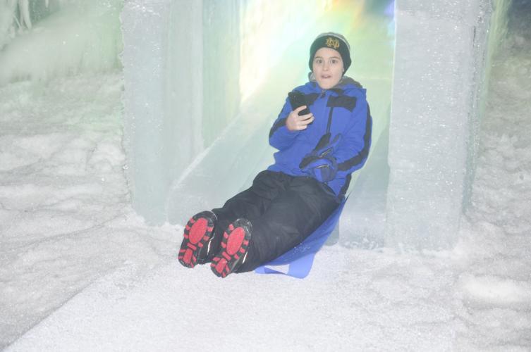 Boy uses cellphone on ice castle slide