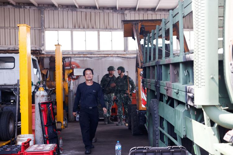 Autos workshop owner Ho Chi-hua walks through his vehicle repair workshop as Taiwan soldiers take part in a drill simulating emergency repairs on damaged military vehicles, in Penghu