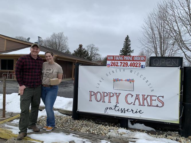 Jacob and Abby Blada stand next to the sign of their business