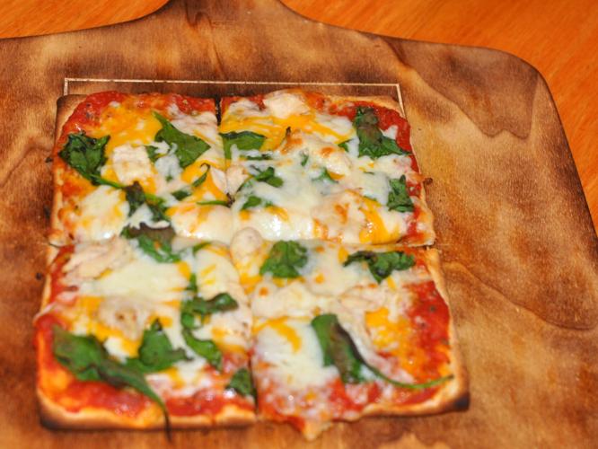 A finished pizza at The Farmstand is placed on a table for a customer to enjoy.