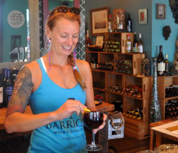 Dana Trilla, co-owner of Barrique Bistro & Wine Bar, is all smiles as she prepares to serve a glass of wine for a customer