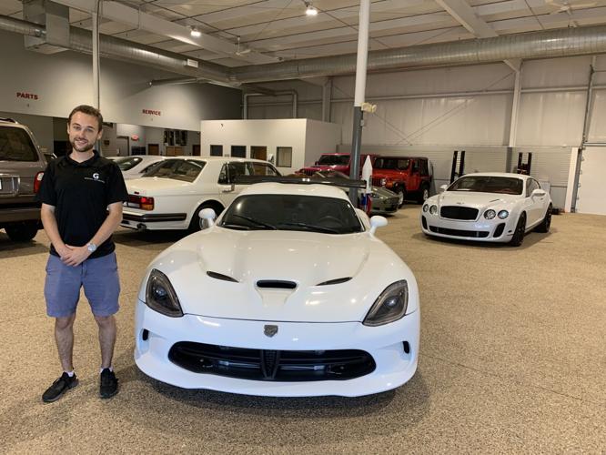 Spencer Giardini stands next to one of the luxury vehicles that his dealership offers