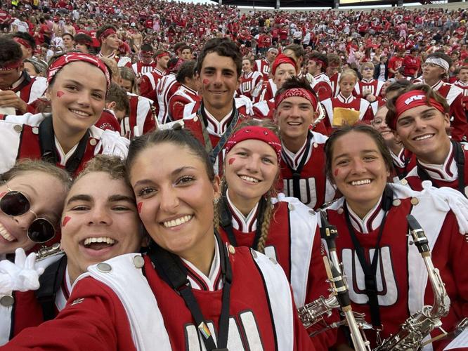 Caleb Monge and other members of the University of Wisconsin marching band pose for a photo in the stands