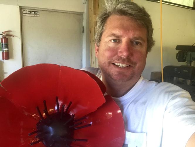 John Larkin stands with a recently-painted poppy sculpture flower that is set to be a part of a larger sculpture (copy)
