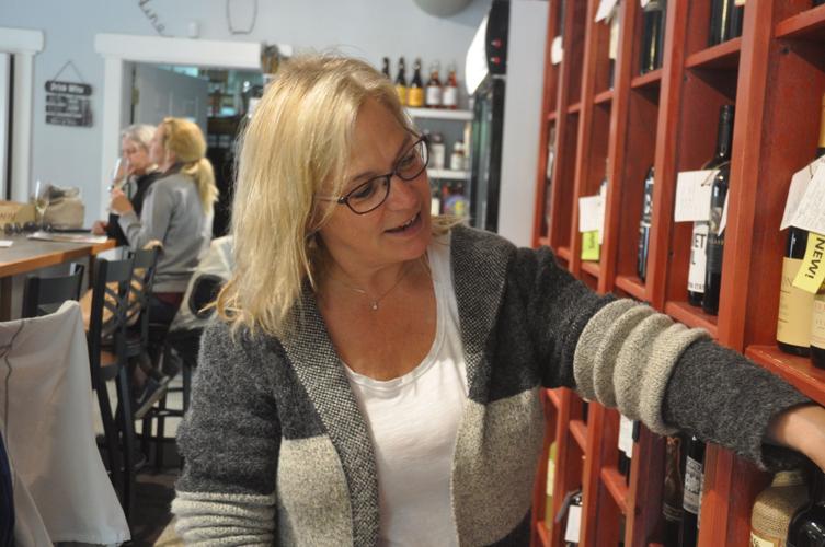 Beth Tumas, owner of the Bottle Shop, sorts through some bottles of wine at her business
