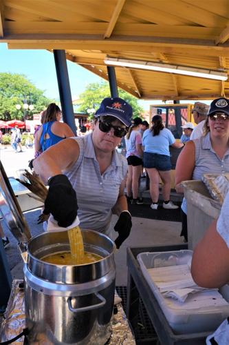 Dipping roast corn on the cob in melted butter at the New Berlin Lions Club corn stand